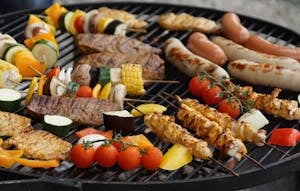 A vibrant assortment of grilled meats, sausages, and vegetables on a barbecue grill.