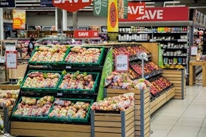 Colorful produce aisle in a supermarket showcasing fresh apples with discount signage.