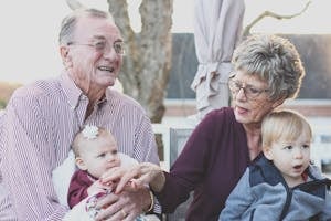 Grandparents spending joyful moments with their grandchildren in an outdoor setting, captured candidly.